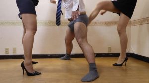 ReiとMatsuriがOL制服姿で哀れな男に金蹴りを放ち、オフィス内で急所を的確に破壊する緊迫の全体像。 - Rei and Matsuri unleash a fierce ballbusting strike in office lady uniforms, perfectly capturing the total destruction of his groin.